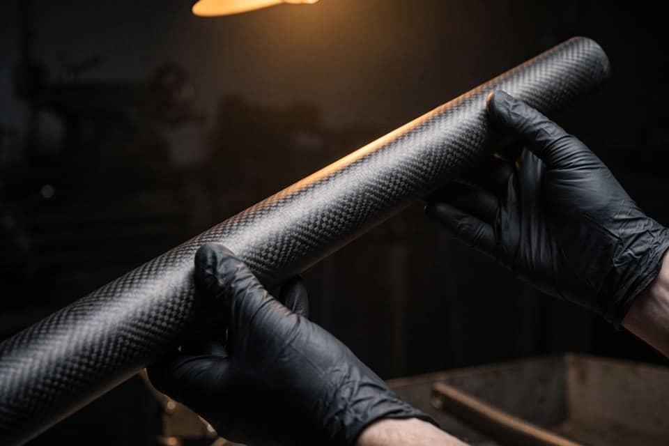 A carbon fibre tube held in gloved hands